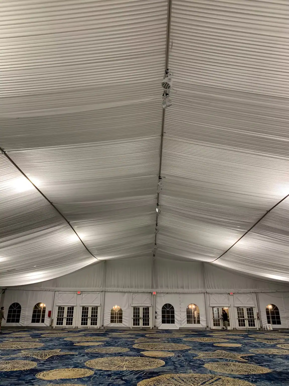 Diffused white house lighting illuminating a draped event tent ceiling