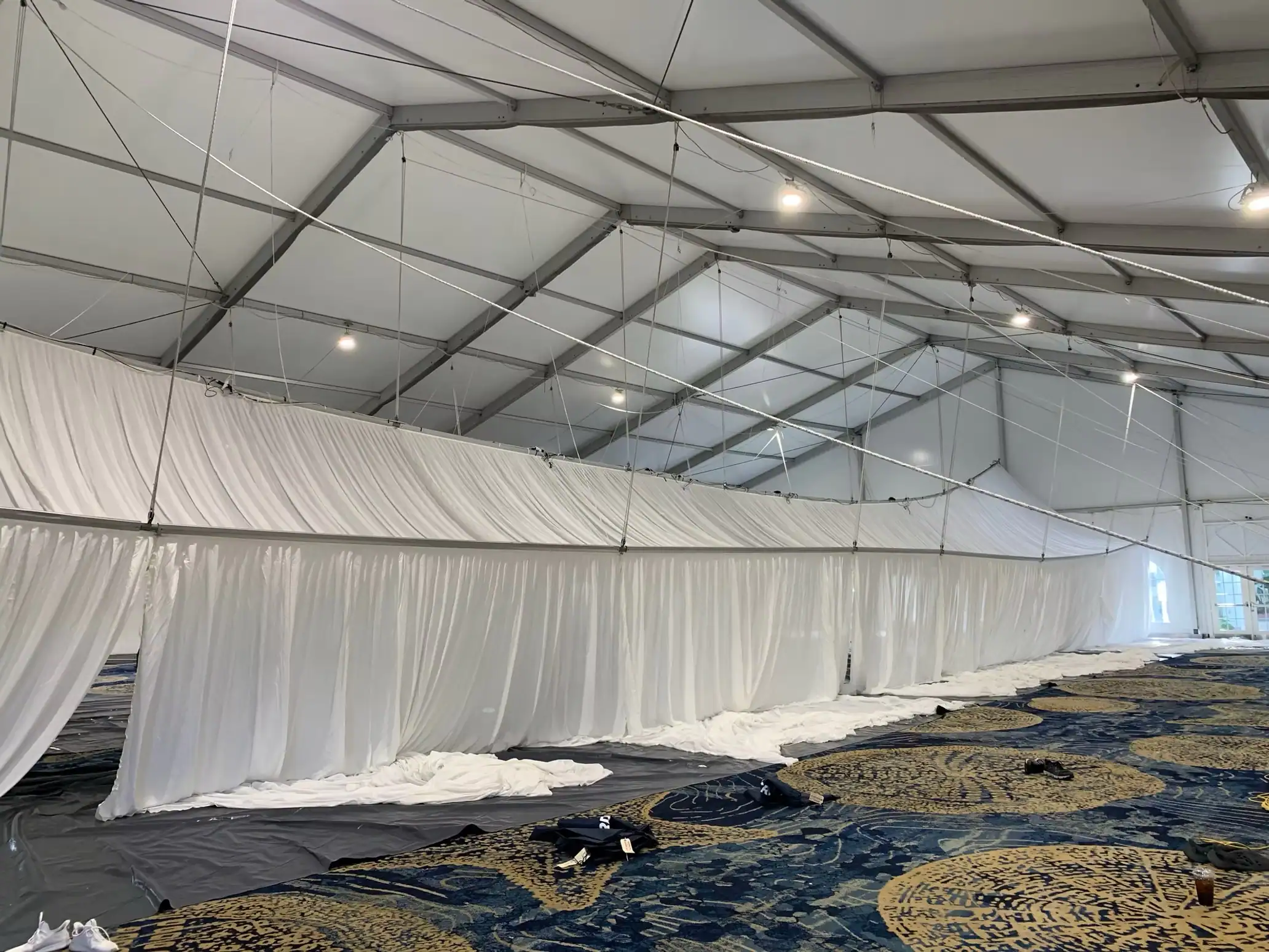 Event tent lighting fixtures installed above ceiling drapes during a permanent lighting upgrade