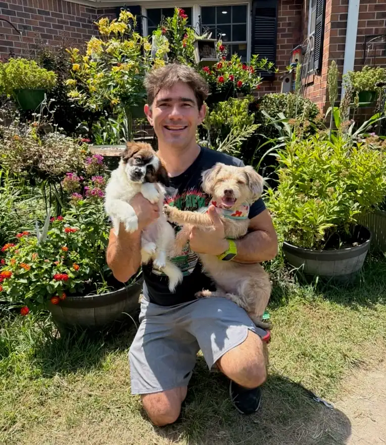 TYLERLIGHT owner holding two dogs in a garden
