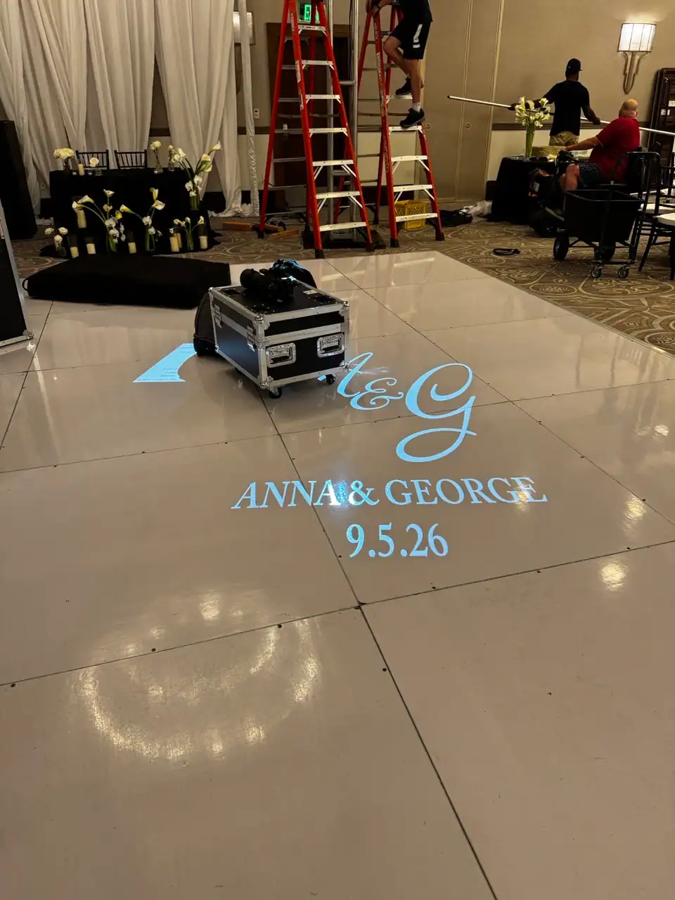 Wedding monogram projected onto a dance floor during event setup