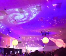 Decorative light patterns projected across the ceiling of a purple-lit event venue