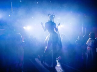 Costumed performer surrounded by theatrical lighting and haze at a Halloween event