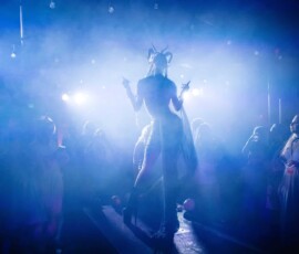 Costumed performer surrounded by theatrical lighting and haze at a Halloween event