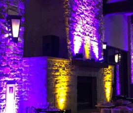 Purple and gold architectural uplighting highlighting textured stone walls at an Orlando property